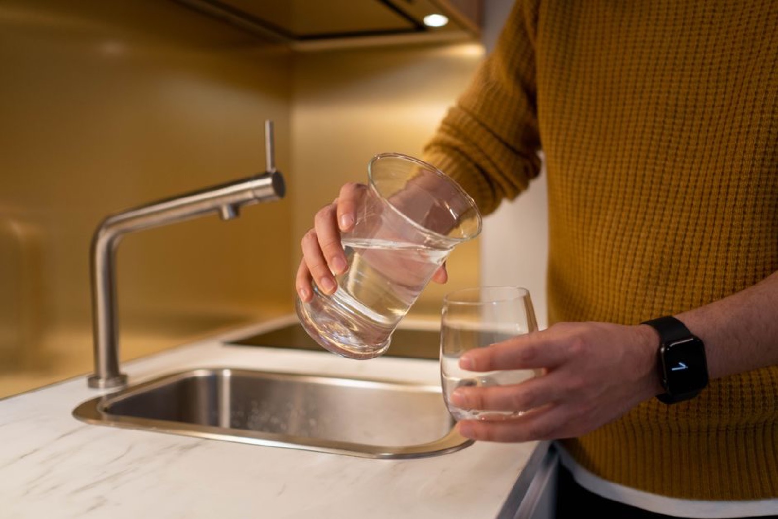 Water filter pitcher on a kitchen counter with a glass of clean filtered water